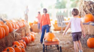 Caregiver and child enjoying a fall festival with pediatric respiratory equipment packed nearby.